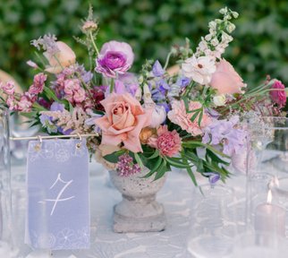 pink, peach, mauve, and purple wedding centerpieces in a stone vase. hanging fabric dutsy blue table number