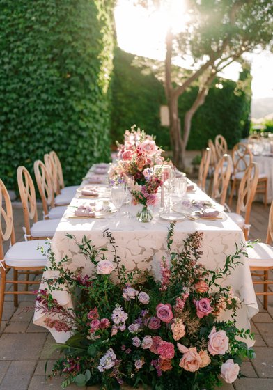patterned white linen with bright flowers. wedding tablescape idea. long dinner table with lush flowers capping end of table