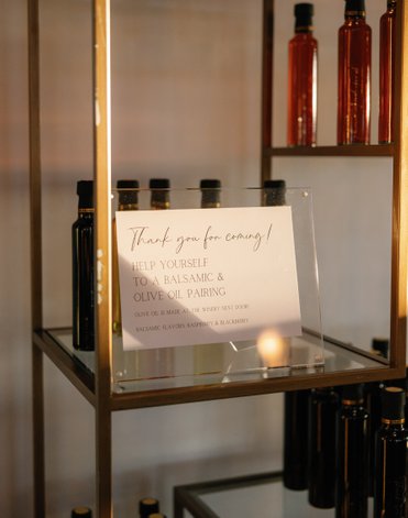 olive oil wedding favors displayed on shelving with a wedding favor sign. 